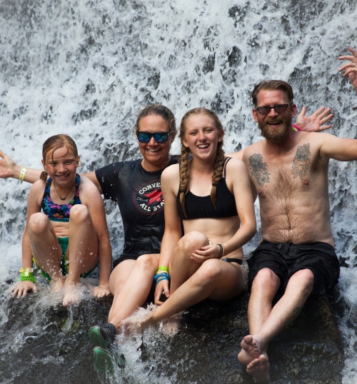 family under a waterfall in costa rican rainforest